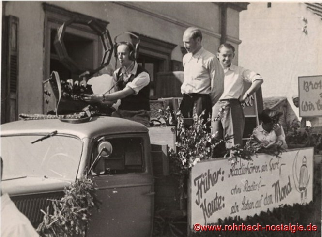 Bei dem Festumzug "100 Jahre selbständige Gemeinde Rohrbach" am 4. September 1949 fährt dieser Wagen mit und macht Reklame für JOBA-Radios. Der Chef der Firma, Josef Bayer, sitzt im ersten Foto auf der Ladefläche (mit Sonnenbrille und weißem Hemd). Die Aufschriften auf dem Wagen lauten: Erstes Bild: "Radio hören... heißt doppelt leben." -- "Mit Lip ist es genau ... 15 Uhr!" (Lip ist eine französische Uhrenmarke, für die mit diesen Worten eine Zeitlang bei der Zeitansage Werbung gemacht wird.) -- "Versuch dein Glück" / "Der runde Tisch" / "Die Saarlandbrille" (Namen von drei beliebten Sendungen von Radio Saarbrücken.) Unteres Bild: "Früher: Radiohören ein Sport - Heute: ohne Radio? - ein Leben auf dem Mond." (Man darf nicht vergessen, dass der Beginn regelmäßiger Rundfunksendungen in Deutschland damals gerade erst etwa 25 Jahre zurückliegt!)