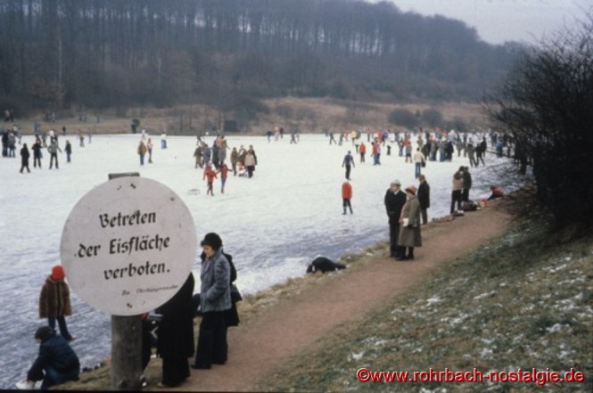 Schlittschuhfahrer und Spaziergänger auf dem zugefrorenen Weiher