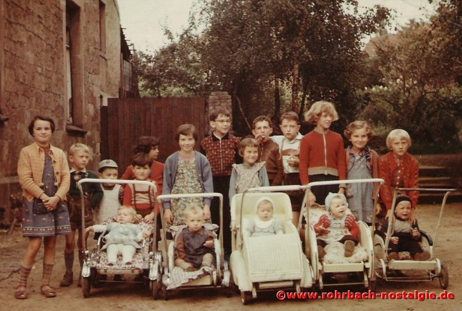 1956 Kinder der Schlawerie neben dem Gasthaus Rohe. Stehend von links: Gertrud Schwarz, Leopold Hubertus, Karlheinz Gehring, Erich Schwarz, Kathi Gehring, Rosel Grell, Joachim Hausen, Gerda Jung, Gerd Jung, Peter Gehring, Gabriele Gehring, Helga Rohe, Ursula Grub. In den Kinderwagen von links: Helga Hector, Michael Würz, Marianne Schorr, Christel Jung und Rudi Lenhard